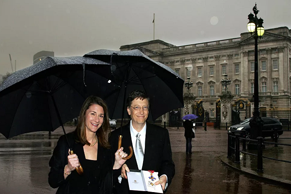 Tỷ phú Bill Gates "khoe" bằng hiệp sĩ danh dự khi đứng cạnh vợ ông bên ngoài Cung điện Buckingham ngày 2/3/2005.
