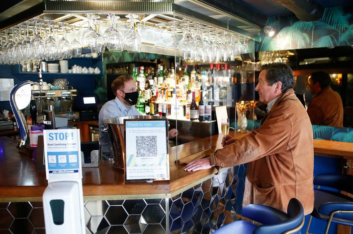 Jonathan Lea, quản lý tại nhà hàng Loxley's, trò chuyện với khách hàng Kim Newton qua tấm kính bảo vệ hôm 17/5.