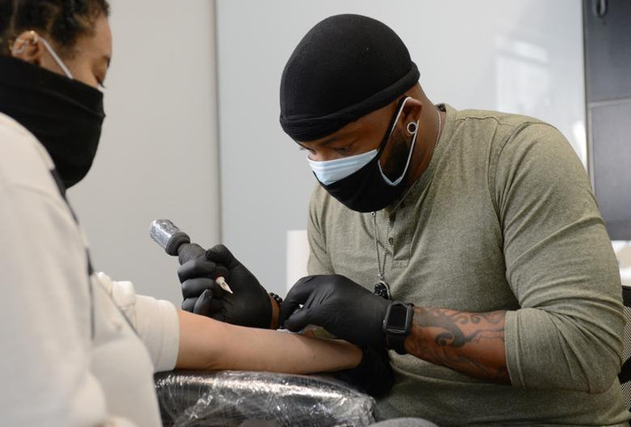 Theo McDaniel đeo khẩu trang cẩn thận khi xăm cho khách hàng tại tiệm Black Ink Atlanta ở Atlanta.