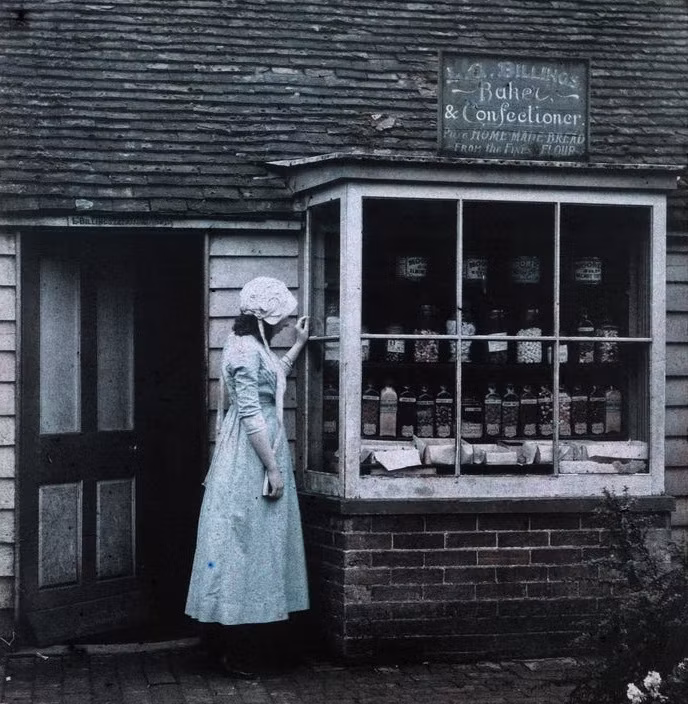 Cô gái đứng trước tiệm bánh có tên Billings ở Anh. Bức ảnh này được chụp trong khoảng thời gian 1910-1915.