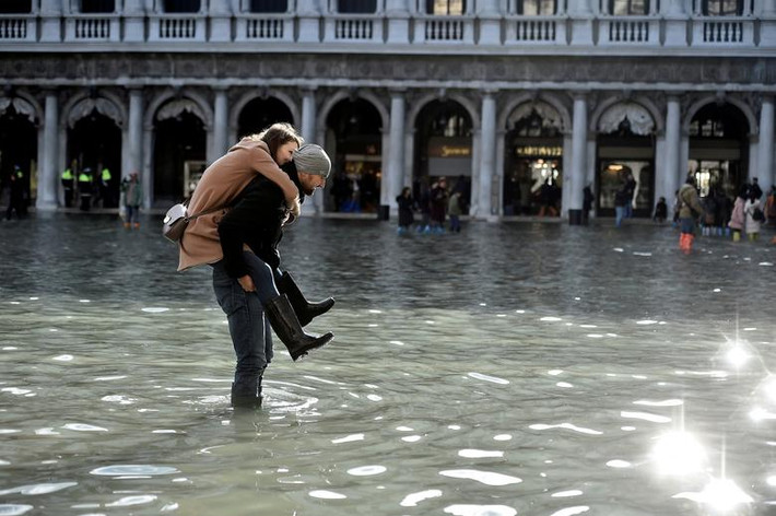Italy: Người đàn ông cõng một cô gái qua khu vực ngập lụt tại Quảng trường St Mark ở Venice ngày 14/11.