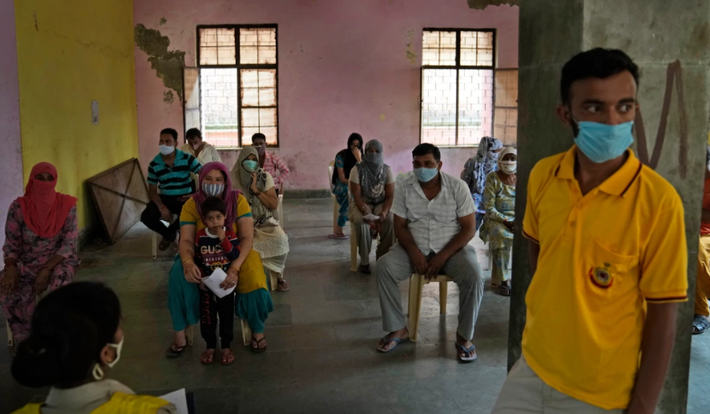 Người dân ngồi trong phòng theo dõi sau khi tiêm vắc xin ngừa COVID-19 ở Nizampur.