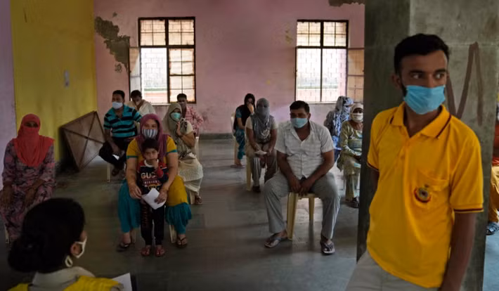 Người dân ngồi trong phòng theo dõi sau khi tiêm vắc xin ngừa COVID-19 ở Nizampur.