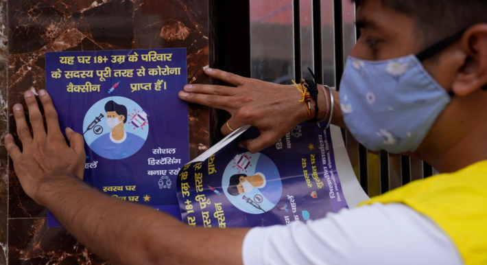 Tình nguyện viên dán tờ thông báo rằng tất cả người trưởng thành trong ngôi nhà này đã được tiêm vắc xin phòng COVID-19 đầy đủ.