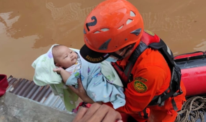 Lực lượng cứu hộ Indonesia sơ tán một em bé sơ sinh ra khỏi khu vực ngập lụt.