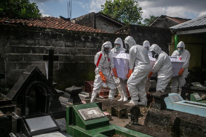 Các nhân viên mặc đồ bảo hộ khiêng quan tài chứa thi thể nạn nhân COVID-19 đi chôn cất tại một nghĩa trang công cộng ở Badran, Yogyakarta, Indonesia, ngày 22/6.