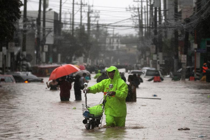 Người đàn ông dắt xe qua con phố ngập lụt ở Vùng Thủ đô Manila. 