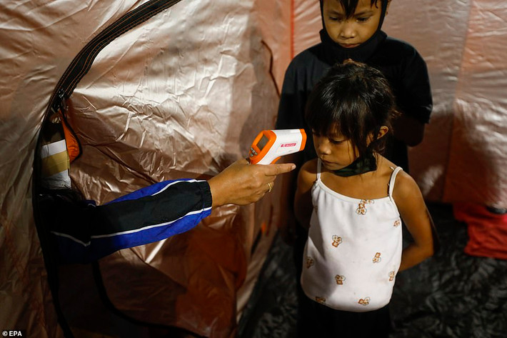 Một bé gái được đo thân nhiệt tại trung tâm sơ tán ở thành phố Quezon. Ảnh: EPA.