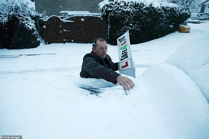 Người đàn ông loại bỏ tuyết trên ô tô ở West Midlands.