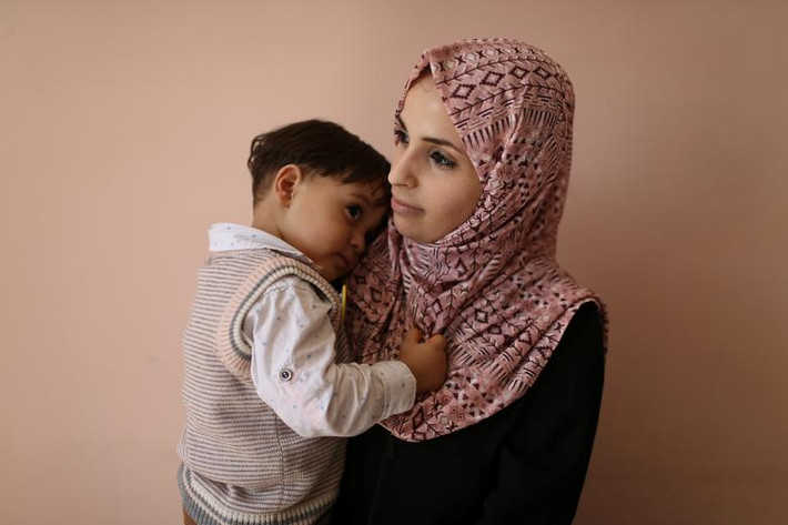 Một phụ nữ Palestine bế em nhỏ tại trung tâm y tế UNRWA trong khu trại Rafah phía nam Dải Gaza tháng 9/2019.