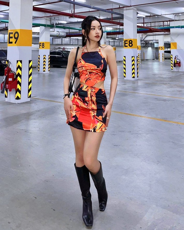 Chi Pu khéo khoe vòng eo thon gọn với áo crop-top cổ yếm và chân váy ngắn, cộng thêm boots da cùng túi Prada.