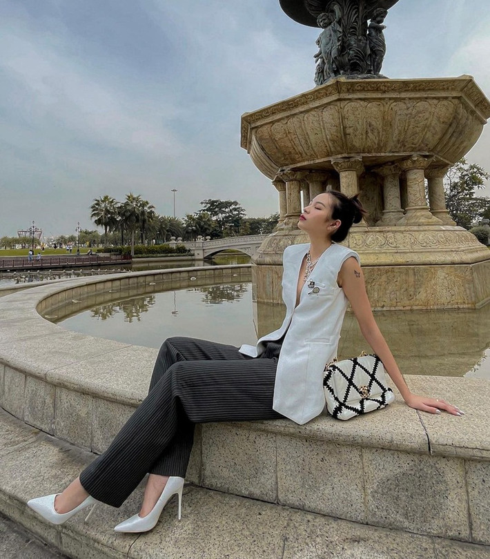 Phí Phương Anh khéo khoe vòng một khi phối áo khoác không tay xẻ ngực sâu cùng quần ống rộng và giày cao gót cổ điển theo tông màu trắng-đen sang chảnh.