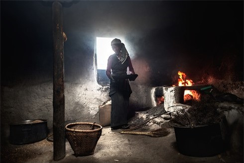 Người phụ nữ đang nướng ngũ cốc làm thức ăn cho gia đình. Ở đây, gỗ rất hiếm, người dân phải sử dụng khô của gia súc làm nhiên liệu