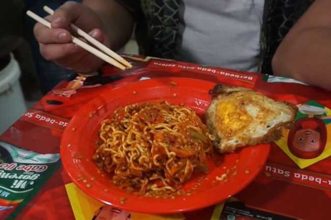 Món ăn này ban đầu xuất phát từ một nhà hàng có tên Abang Adek, nằm ở khu vực gần Jakarta. Tại đây, bạn có nhiều sự lựa chọn các món mỳ Indomie khác nhau, tuỳ chỉnh hương vị và mức độ gia vị. Trong đó, loại cay nhất được thêm 100-150 trái ớt sừng cay, bao trùm lên toàn bộ bát mỳ Indomie thông thường, khiến nó đỏ rực như lửa.