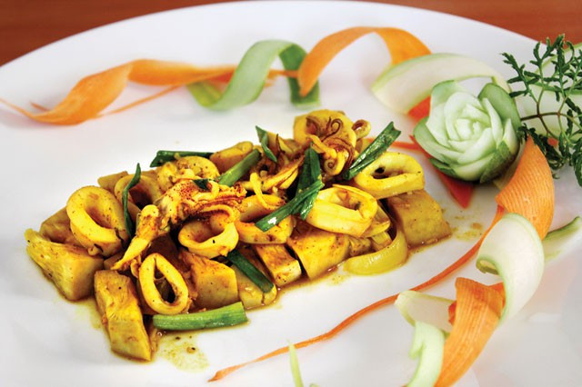 Phi thơm tỏi, cho mít luộc xé vào xào thơm. Thêm bột nghệ, nước mắm, đường, hạt nêm, hạt tiêu vào xào đều tay. Khi mít thấm gia vị và nước sánh lại thì cho mực và hành tây vào xáo. Mực chín thì cho hành lá, húng quế vào và tắt bếp. Cho mít non xào mực ra đĩa và rắc hạt tiêu lên trên.