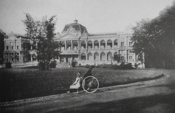 Một phụ nữ ngồi trong khuôn viên Dinh Toàn quyền Sài Gòn, nay là dinh Thống nhất.