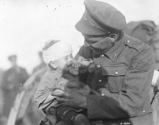 Bức ảnh lịch sử chụp binh sĩ Canada đang cố gắng an ủi, trấn an một em bé người Bỉ bị thương trong Thế chiến 1. Mẹ của em bé này thiệt mạng trong một cuộc pháo kích tháng 11/1918.