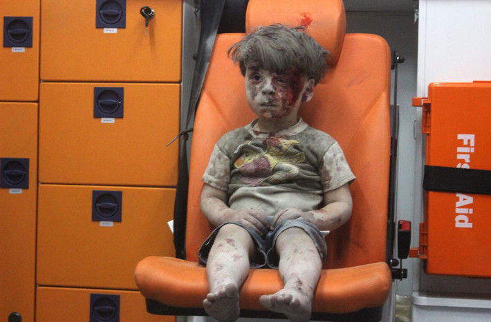 Cậu bé Omran Daqneesh dính đầy bùn đất và máu ngồi trong xe cứu thương sau một cuộc không kích ở Aleppo, Syria tháng 8/2016. Lực lượng cứu hộ mất gần 1 giờ để đào cậu bé ra ngoài từ đống đổ nát. Một cuộc không kích ở Syria phá hủy ngôi nhà của Omran sống cùng bố mẹ và hai anh chị em.