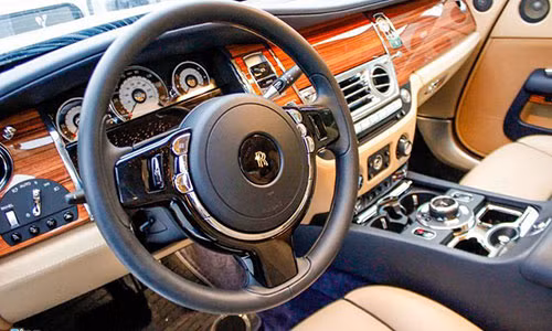 Cận cảnh bên trong chiếc Rolls-Royce Wraith của Phan Thành. Vô lăng ba chấu kiểu truyền thống trên Rolls-Royce. Nội thất bọc da xanh cùng tông màu ngoại thất và những tấm gỗ cao cấp được chế tác hoàn toàn thủ công.