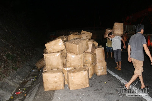 Hàng chục thùng trái cây trên xe tải gặp nạn được thu gom trong nỗ lực thông tuyến quốc lộ. Ảnh: Quang Thành