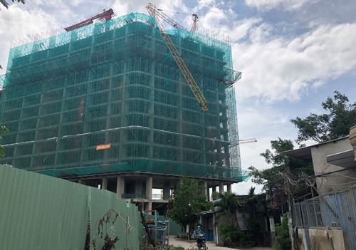 Người dân ở con hẻm cạnh công trình, nơi cần cẩu oằn xuống, treo lơ lửng trong khi bên dưới người dân qua lại.