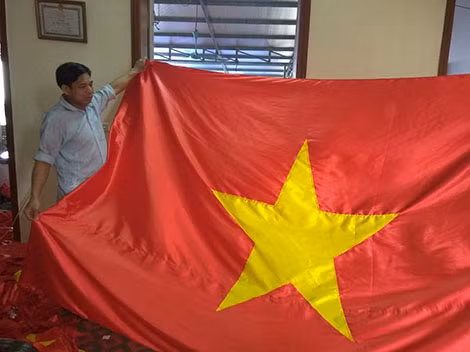 Nghệ nhân Nguyễn Văn Phục với lá cờ mới hoàn thành.