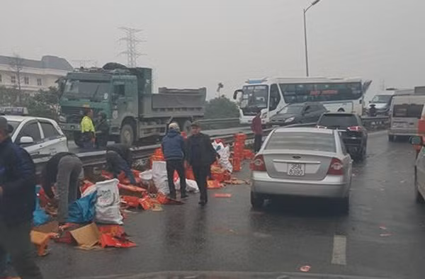 Người dân tập trung nhau giúp tài xế thu dọn hàng bị rơi xuống đất.