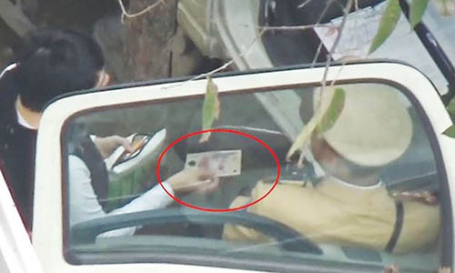 Hình ảnh người cho là vi phạm đưa một vật giống tiền cho CSGT Hà Nội để "làm luật" nhanh. Ảnh cắt từ clip.