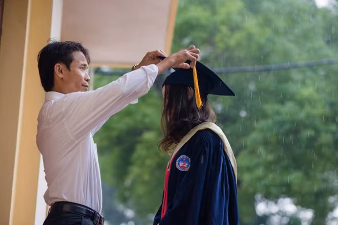 Ngày 15/11, bức ảnh kỷ yếu "Cha và con gái" khi trời mưa nặng hạt trở thành tâm điểm chú ý trên mạng. Khoảnh khắc này không quá đặc biệt, song câu chuyện về người cha nghèo bắt xe từ 4h sáng lên thành phố để chụp hình cùng con khiến mọi người cảm thấy ấm lòng. Ảnh: Nguyễn Thái Sơn.