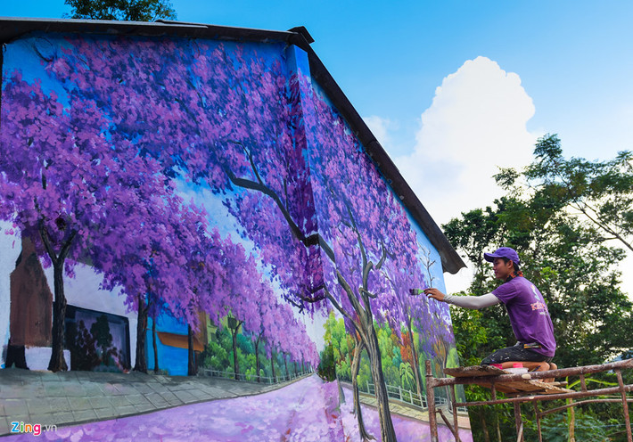 Các họa sĩ đang hoàn thành bức tranh về khu vườn hoa mai anh đào trên tường nhà dân.