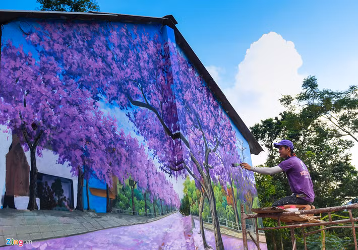 Các họa sĩ đang hoàn thành bức tranh về khu vườn hoa mai anh đào trên tường nhà dân.
