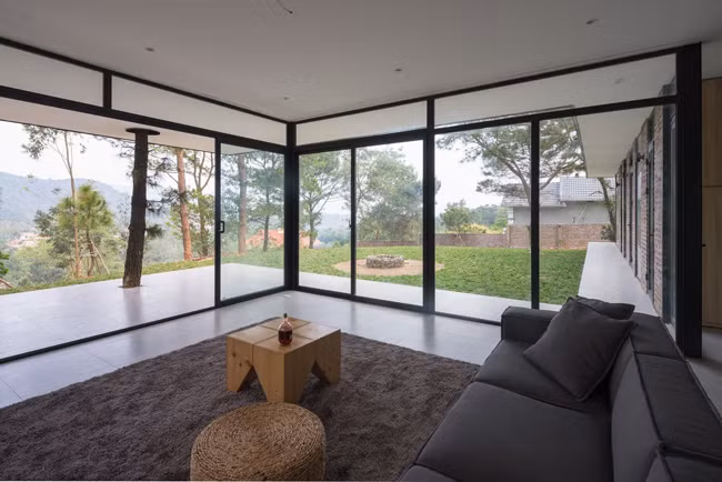 Khối phòng khách và phòng ngủ vuông góc, tạo thành một khoảng sân cỏ rộng rãi, bằng phẳng trước hiên nhà làm chỗ chơi cho lũ trẻ mà không làm cản trở tầm nhìn từ bên trong. Hầu hết các bức tường đều có cửa kính lớn, giúp lan tỏa ánh sáng tự nhiên môt cách tốt nhất.