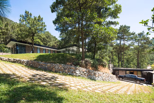 Vì thế, công trình được chia thành 2 phần, phần đất thấp hơn bên dưới được bố trí gara để xe và một phòng phụ đa năng, phần đất cao bên trên được xây thành nhà chính. Tổng diện tích công trình lên tới 1000m2.