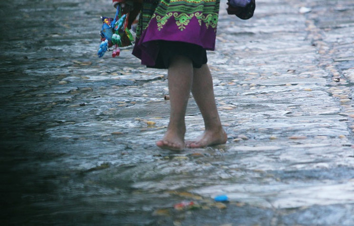 Đôi chân trần không dép bước bộ dưới mưa lạnh của em nhỏ đi qua các điểm du lịch ở thị trấn Sa Pa mời khách mua hàng.