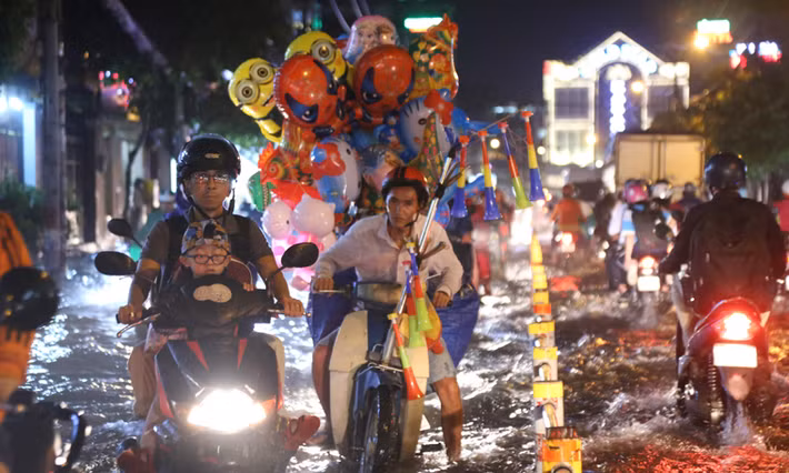 Nhiều người mưu sinh vô cùng vất cả lội qua tuyến đường ngập nước sau cơn mưa tối 26/9.