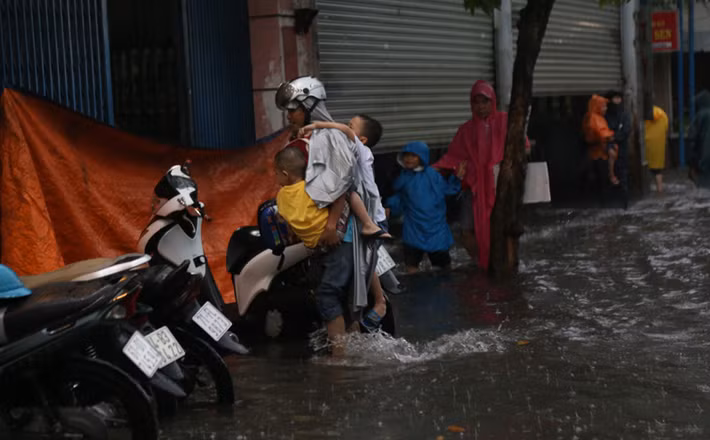 Nước ngập sâu tới đầu gối người lớn nên các bậc phụ huynh không dám để con lội nước vì sợ té xuống cống mỗi khi có xe đi qua tạo sóng.