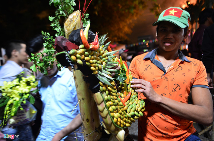 Một người tham gia tranh đồ cúng khoe "chiến lợi phẩm" là một phần hình con rồng được trang trí bằng trái cây đặt ngay bàn thờ ông Tiêu. Nhiều người giành được các loại đồ cúng như bánh, trái cây, hoa, giỏ hoa, kệ thờ bánh, trái... tin là những thứ sẽ mang lại may mắn nên họ mang về đặt lên bàn thờ trong nhà.