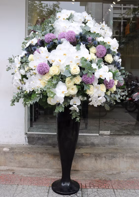 Một bình hoa khác có giá 70 triệu đồng cũng khiến người mua phải chú ý. Bình hoa này gồm có hoa hồng trắng nhập khẩu giá 120.000 đồng/cành, lan hồ điệp 350.000 đồng/cành, hoa sao Hà Lan 180.000 đồng/cành và một số lá nhập nhuộm màu vàng, màu bạc. (Ảnh: Dân trí).