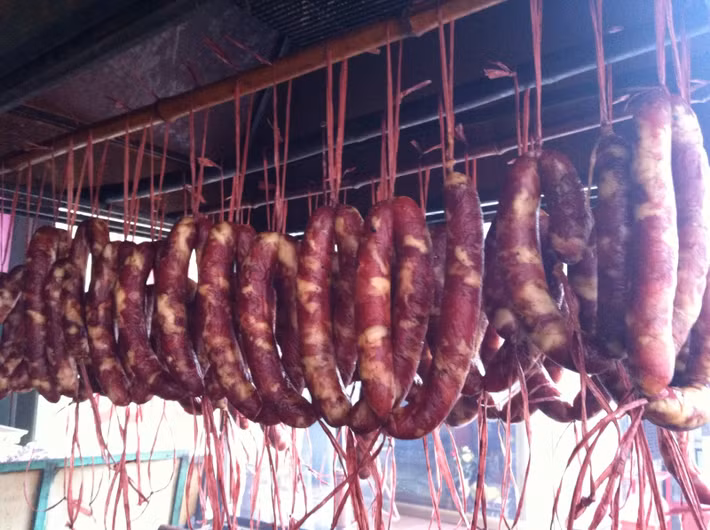 Lạp sườn: Lạp sườn Cao Bằng có vị ngon đậm đà của thịt nạc vai ướp các loại gia vị, vị chua chua, thơm ngậy của thịt hun khói và lá, quả mác mật, thêm một chút vị thơm của củ gừng núi, dai dai của vỏ lòng non bào mỏng và đặc biệt là không dùng chất bảo quản. Lạp sườn Cao Bằng chế biến bằng cách rán vàng đều, nướng trên than hoa rồi thái lát mỏng chấm tương ớt, ăn kèm với rau thơm, dưa chuột. Ảnh: Caobangtv.