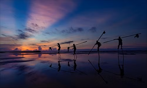 Với 3 mặt giáp biển và hơn 3.000 km đường bờ biển, vị mặn mòi của biển cả đã trở nên thân thương, đi sâu vào tiềm thức mỗi người dân Việt Nam. Không khó hiểu khi rất nhiều tác phẩm gửi về cuộc thi ảnh "Dấu ấn Việt Nam" lấy đề tài cuộc sống tại các làng chài ven biển. Trong ảnh là những ngư dân tại bãi biển Hải Lý (Nam Định) sẵn sàng cho một ngày làm việc mới khi trời vừa hừng đông. Ảnh: Đặng Thị Thúy Mai.