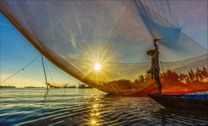 Đến biển Cửa Đại (Quảng Nam), du khách nên đi đón bình minh trên cửa biển và xem ngư dân bắt cá bằng rớ. Những chiếc rớ được làm bằng một tấm lưới lớn, rộng khoảng 80-130 m2, lung linh trong ánh nắng tạo nên một cảnh đẹp nên rất thơ. Ảnh: Lê Thị Minh Nguyệt.