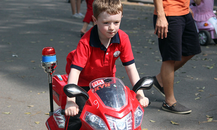 Một em bé nước ngoài thích thú với chiếc mô tô siêu nhỏ trên phố đi bộ Hà Nội.