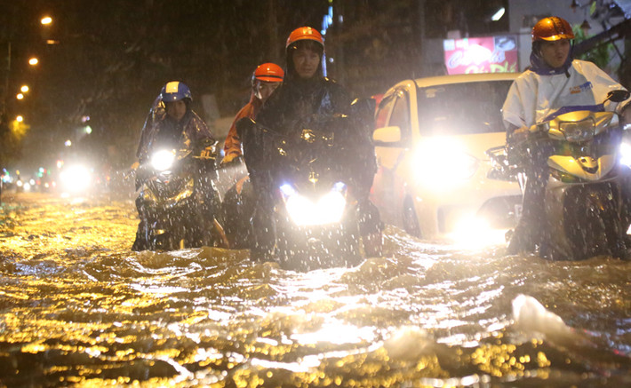 Người dân bì bõm lội qua khu vực ngập nặng để tìm đường trở về nhà trong đêm.