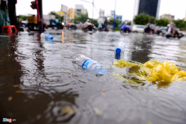  Người dân Sài Gòn lội nước băng qua đường ngập. Rác nổi lềnh bềnh sau cơn mưa.
