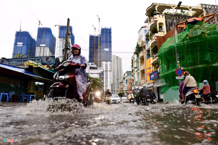 Phương tiện di chuyển khó khăn qua dòng nước ngập trong hẻm 602 Điện Biên Phủ. Con đường này dẫn ra đường Nguyễn Hữu Cảnh, một nơi thường xuyên bị ngập sau mưa.