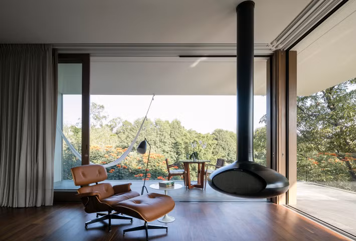 Một góc không gian riêng tư để thư giãn với tường được làm hoàn toàn bằng kính trong suốt, cho phép quan sát toàn bộ khung cảnh thiên nhiên tuyệt đẹp bên ngoài.