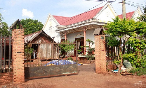 Cạnh tường gạch là ngôi nhà gỗ truyền thống của người dân tộc Ê - Đê. Ảnh: Người đưa tin.