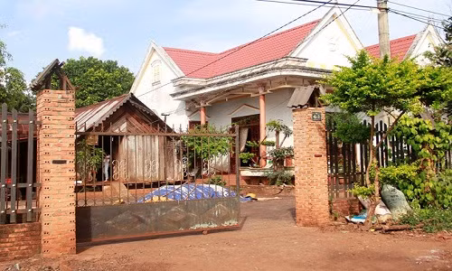 Cạnh tường gạch là ngôi nhà gỗ truyền thống của người dân tộc Ê - Đê. Ảnh: Người đưa tin.