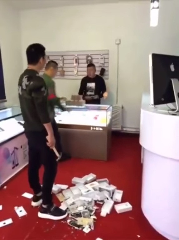 Để thể hiện độ giàu có, chàng thanh niên Trung Quốc chồng tiền mua 10 chiếc iPhone rồi đập nát. Ảnh: Youtube.