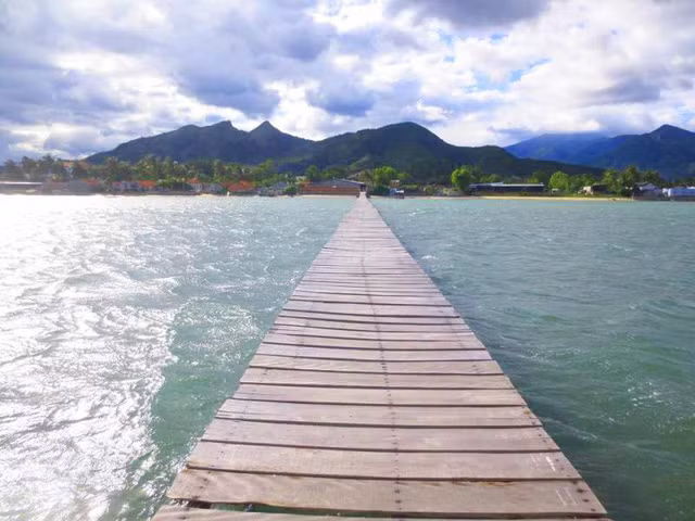 Cây cầu gỗ không có tay vịn, nằm đơn độc giữa bốn bề là biển xanh hun hút. Đứng ở trên cầu trông ra biển, mọi thứ như mênh mông và cây cầu cũng vì thế “đánh lừa” người nhìn, cứ như chạy dài vô tận theo đến đường chân trời.